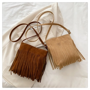 Detail of suede crossbody bags with long fringe tassels in brown and khaki colors