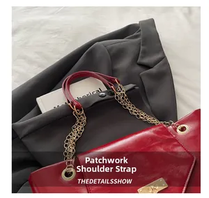 Detail of burgundy leather shoulder bag with golden chain and spliced strap design