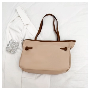 Vue à plat d'un grand sac bandoulière beige contrasté avec des lanières marron