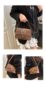 Detail view of brown leather crossbody bag featuring a large silver buckle and strap