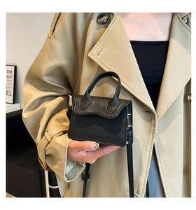 Gros plan du mini sac à main en cuir grainé noir avec détails dorés et poignée rigide