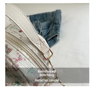 Close-up of reinforced stitching and gold metal hardware on floral mini handbag