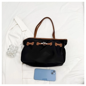 Vue de dessus d'un sac cabas noir avec fermoir rotatif argenté et lanières en cuir marron
