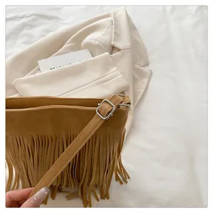 Close-up of dark brown suede shoulder bag with dense fringe tassels and silver buckle