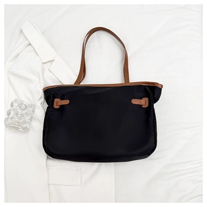 Vue détaillée de dessus d'un grand sac cabas en tissu noir avec anses en cuir marron