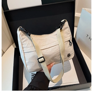 Detail of off-white pleated crescent crossbody bag with metal logo in a luxury gift box