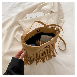 Detail of tan suede tassel bag showing interior capacity for phone and cosmetics