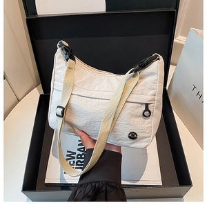 Detail of off-white nylon dumpling bag with adjustable shoulder strap and buckle