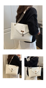 Close-up of white PU leather tote bag with gold deer charm and chain shoulder strap