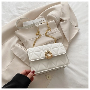 Détail du sac bandoulière blanc matelassé avec chaîne dorée sur une veste chic