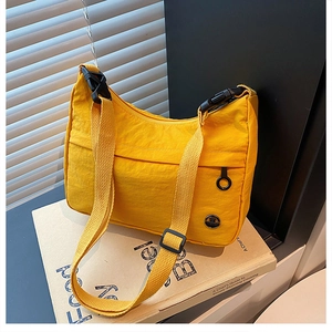 Detail of yellow nylon crossbody bag with adjustable black strap and round logo