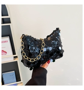 Detail of black sequined underarm bag with thick gold chain strap and moon-shaped design