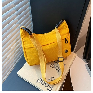 Macro detail of yellow nylon crossbody bag featuring round logo and plastic buckle