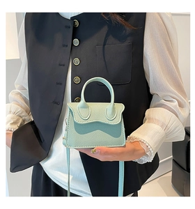 Détail du mini sac à main vert menthe à texture litchi avec poignée et finitions dorées