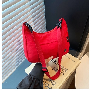 Detail of red crescent nylon crossbody bag with adjustable strap and metal logo