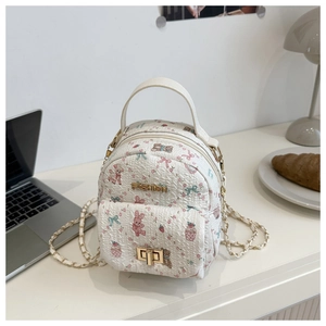 Detail of white mini backpack with floral cartoon patterns and gold metal clasp