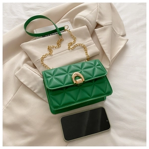 Detail of green quilted leather texture and gold horseshoe buckle on crossbody bag