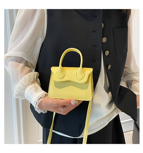 Gros plan d'un mini sac jaune en cuir grainé avec une poignée semi-circulaire chic