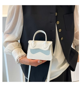 Détail macro du mini sac blanc en cuir litchi avec rabat incurvé et petite poignée