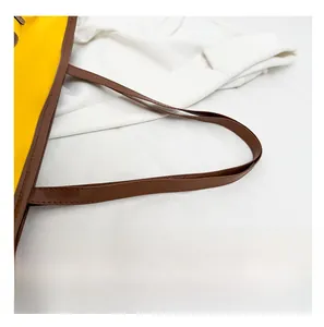 Détail des poignées en cuir et des coutures contrastées sur un sac cabas bicolore