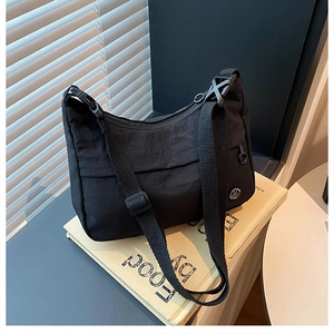 Close-up of black nylon crossbody bag featuring adjustable strap and metallic logo detail