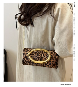 Close-up of leopard print shoulder bag with large gold circular buckle and chain strap