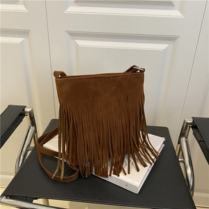 Brown suede crossbody bag with fringe decoration shown in an indoor studio setting