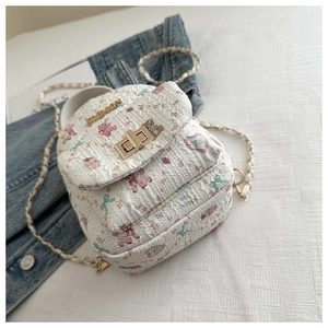 Detail eines weißen Stepprucksacks mit Bärenprint und goldenem Drehverschluss