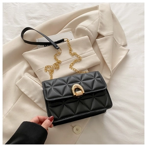 Détail du sac matelassé noir avec fermoir fer à cheval doré sur un blazer beige