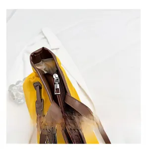 Détail de la fermeture éclair argentée et garniture en cuir brun sur le sac jaune