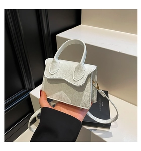 Close-up of white mini PU handbag featuring pebble grain leather and wave edge flap detail