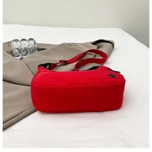 Detail view of red canvas crossbody bag with adjustable strap and M Fashion logo