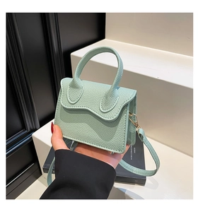 Close-up of mint green litchi grain mini handbag with wave flap and round handle