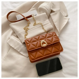 Detail of brown quilted shoulder bag with gold horseshoe clasp on a beige blazer