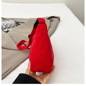 Side view of red nylon crossbody bag showing thickness and adjustable fabric strap