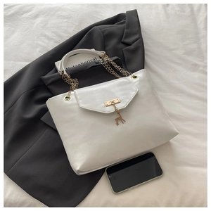 Detailed top view of white leather tote with gold deer charm and elegant chain strap