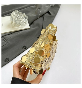 Détail d'un sac de soirée triangulaire à paillettes dorées avec bandoulière chaîne