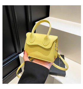 Detail of yellow lychee textured leather mini handbag with top handle and strap
