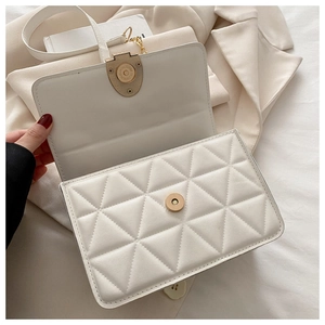 Makro-Detail der weißen Stepptasche mit goldenen Metallteilen und Magnetverschluss