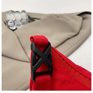Detail of red nylon waist bag featuring durable black plastic buckle and smooth zipper