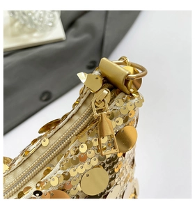 Détail d'un sac demi-lune à paillettes dorées avec fermeture éclair métallique