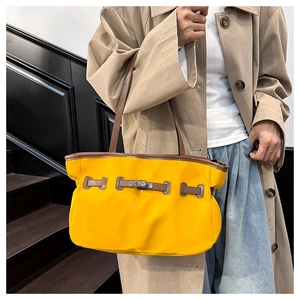 Détail du sac cabas en nylon jaune avec garniture en cuir marron et fermoir sur escaliers