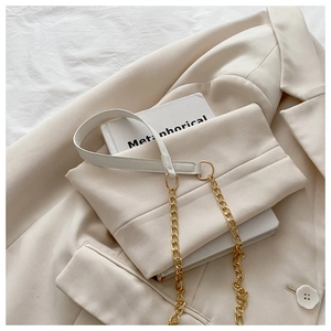 Detail einer cremefarbenen Stepptasche mit goldener Kette auf passendem Blazer