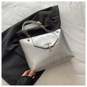 Detailed close-up of silver tote bag with golden chain handle and deer pendant