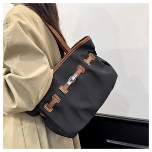 Détail du sac cabas bicolore avec fermoir rotatif argenté et anses en cuir marron