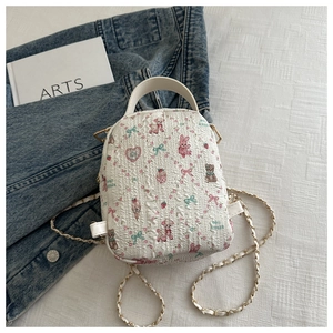 Detail von süßen Kaninchen- und Bärenmustern auf weißem Minirucksack mit Metallkette