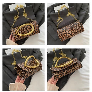 Detail of leopard print crossbody bag featuring a large gold round handle and chain strap