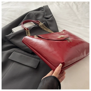 Detail of red glossy patent leather tote with golden chain and deer pendant