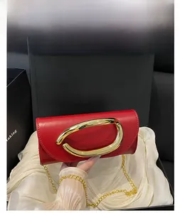 Detail of red leather evening bag featuring a bold gold circular metal buckle and chain