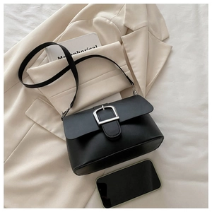 Close-up of minimalist black leather crossbody bag with silver buckle and phone for size